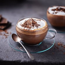 A glass of mocha coffee topped with foam