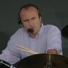 Phil Collins performing with a drum kit during a live rendition of “In the Air Tonight”