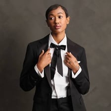 A person wearing a formal black tuxedo suitable for a black-tie wedding