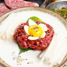 A plate of sashimi beside a serving of steak tartare.