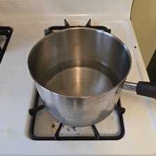 A cooking pot boiling on a stovetop