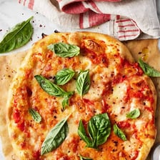 Fresh basil leaves scattered over a margherita pizza.
