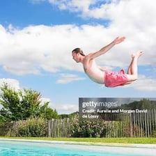 An outdoor swimming pool where someone is diving into the water.