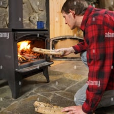 A person adding a log to a burning campfire
