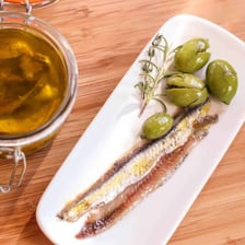 Salt-cured anchovies arranged on a plate.