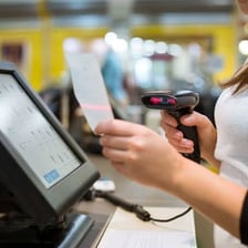 A retail cashier ringing up a customer's purchase at a register.