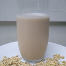 A glass and bottles of oat milk