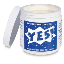 Thick paste in an open container beside craft materials.