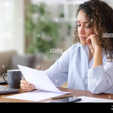 A person closely examining a document at a desk.