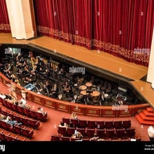 Musicians performing in an orchestra pit below a theater stage.