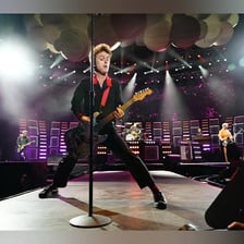 Green Day performing as a rock band onstage.