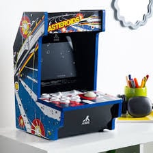 A classic Atari arcade game display featuring Asteroids or Space Invaders.