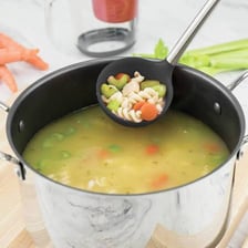 A ladle scooping stew from a cooking pot.