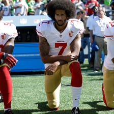 A person kneeling with one knee on the ground during a protest