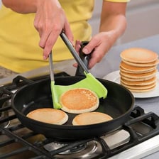 A spatula turning a pancake in a skillet.