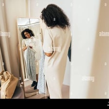 A person checking the fit of clothing in a fitting-room mirror