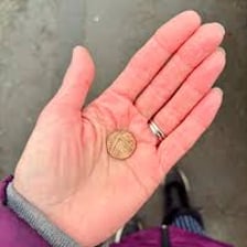 A hand pinching and holding a penny.