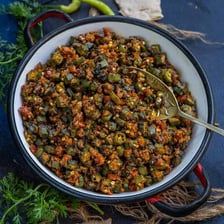 Fresh green okra pods beside a serving of bhindi masala
