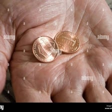 Two pennies held in a person’s hand, illustrating the phrase “two cents”