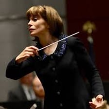 An orchestra conductor signaling musicians to begin.