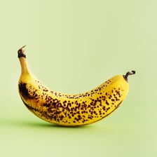 A banana with small fruit flies nearby.