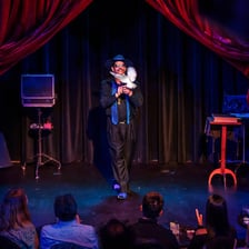 A magician performing before an audience on a stage.