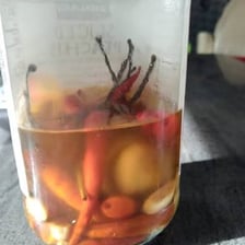 A glass of water beside a bright orange habanero pepper.