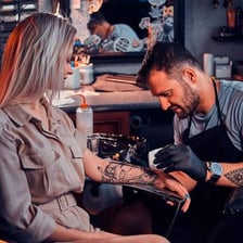 A tattoo artist working on a client in a tattoo studio