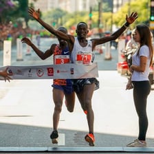 An athlete crossing the finish line just ahead of a competitor