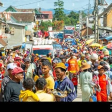 People standing closely around an object in the middle of a crowd.