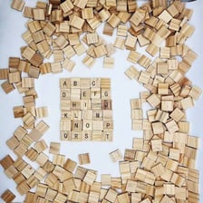 A blank Scrabble tile displayed beside lettered tiles.