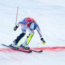 An alpine skier weaving between gates on a slalom course.