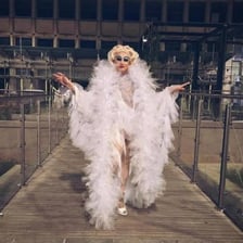 A drag performer wears a feather boa as part of a costume.