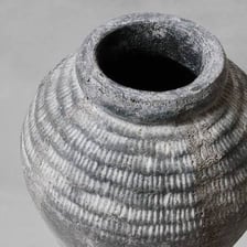An aged, weathered object with a gray, worn appearance.