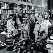 A knowledgeable expert standing among books and reference materials.