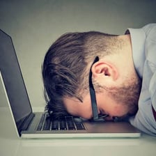 A person nodding off while seated at a desk.