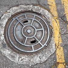 A manhole cover set into a paved road.