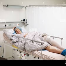 A patient rests in a hospital bed during recovery after surgery.