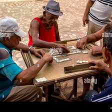 People in Cuba playing dominoes around a table.