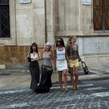 A group of female friends walking together in a Spanish city.