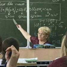 A teacher writing on a classroom chalkboard