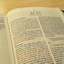 An open Bible displaying the Book of Acts.
