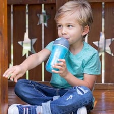 A toddler drinking water from a sippy cup.