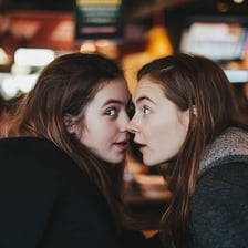 Two people whispering to keep a conversation private