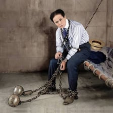 A stage magician performing an escape from chains and restraints.