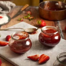 Glass jars containing colorful homemade fruit preserves.