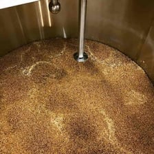 A brewer stirring a mash of crushed grain in a mash tun