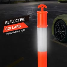 A reflective post beside a road catches the light from a vehicle’s headlights.