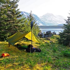 A tarp shelter stretched between trees at a campsite