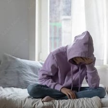 A teenager sitting alone and appearing dejected